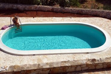 Piscina interrata Ovale 700 cm con scala in acciaio inox e liner Skysand color sabbia, perfetta per un’area relax dallo stile mediterraneo.