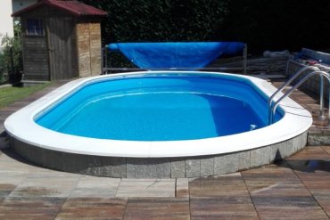 Piscina interrata Skyblue Ovale 600 cm con liner azzurro intenso, bordo massello bianco antiscivolo e rivestimento esterno in pietra naturale per un’eleganza rustico‑chic.